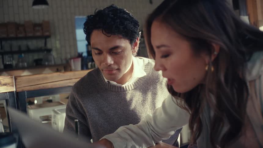 Woman writing and talking with her colleague next to her