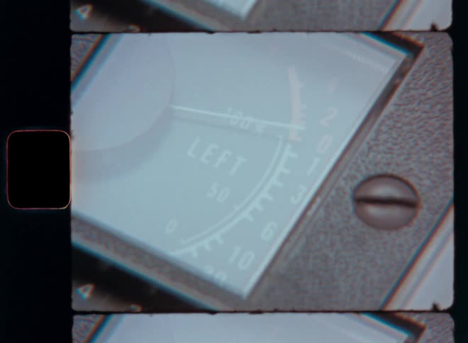A circular gauge with a needle jumping up and down captured on vintage film