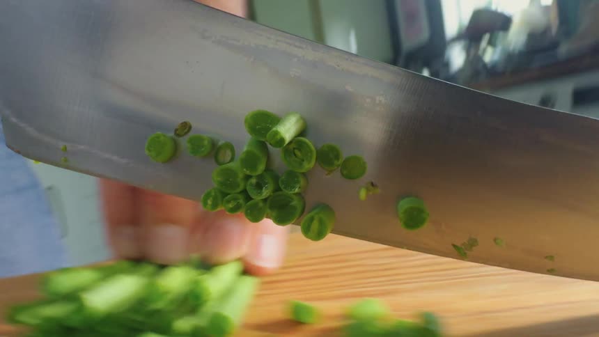 Knife cutting green vegetable
