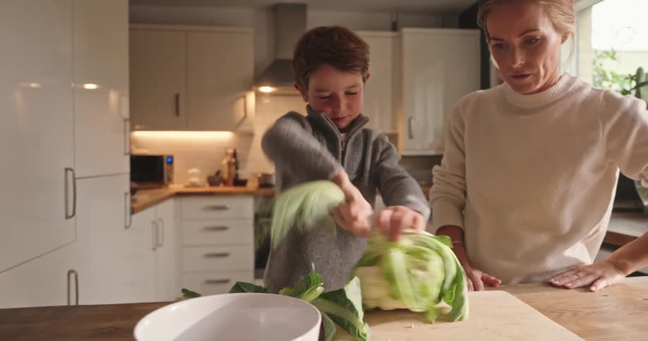 Son ripping leaves off a cabbage while his mother watches