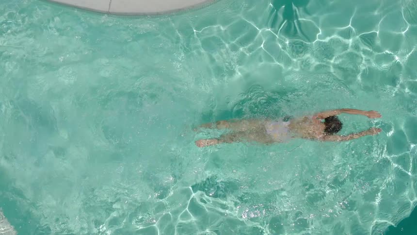 A woman swimming in a pool with clear turquoise water