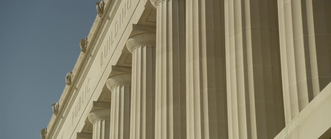 The pillars of a government building tower overhead