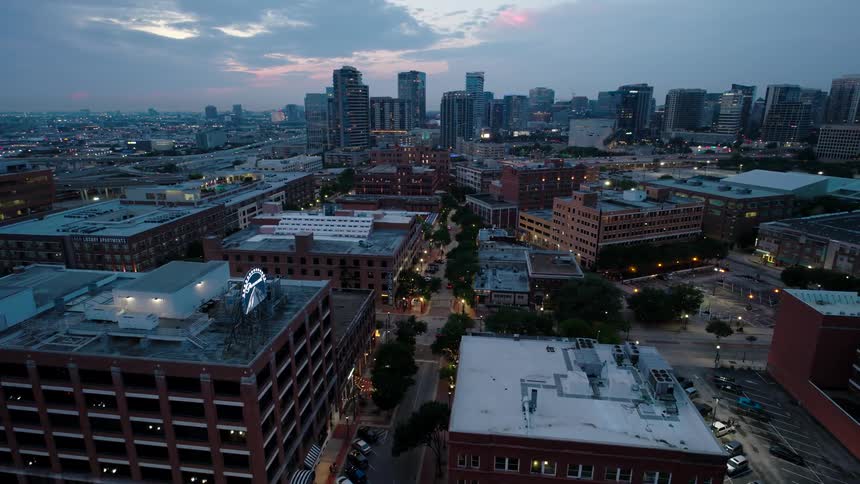 An aerial view of a cityscape at twilight with the downtown buildings illuminated