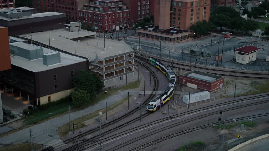 A train turns left as the track bends into a residential neighborhood