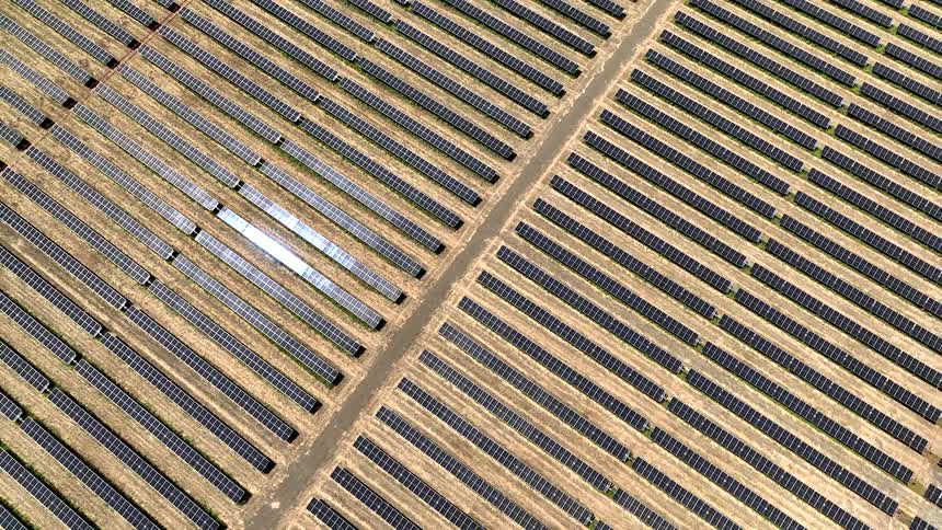 Aerial view of a large solar farm with rows of photovoltaic panels arranged in a grid pattern