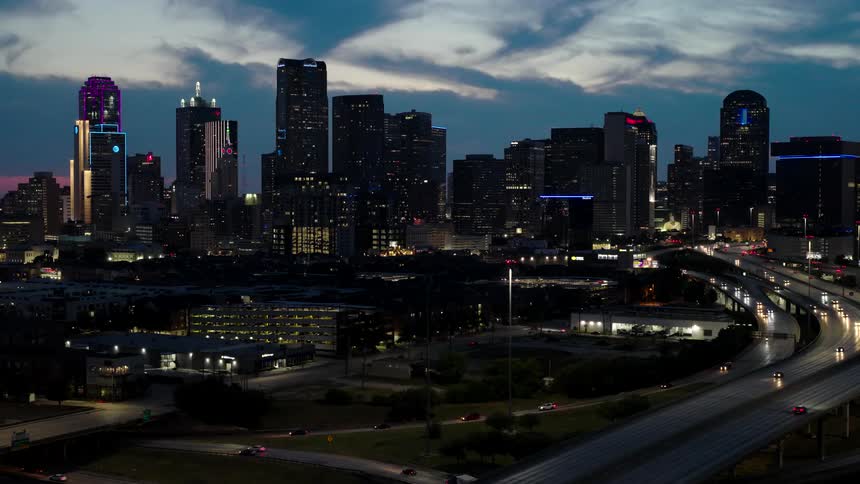 Aerial view of a viaduct and highways passing through metropolises with skyscrapers at night