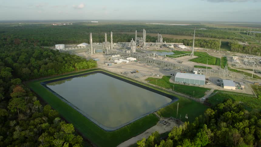 Industrial refinery with tall distillation columns and complex piping networks during sunrise or sunset