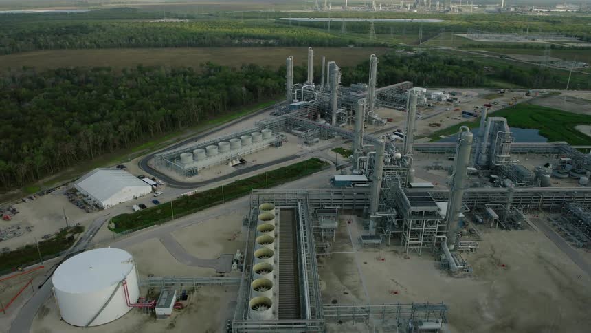 Aerial view of a refinery factory in a remote setting surrounded by trees