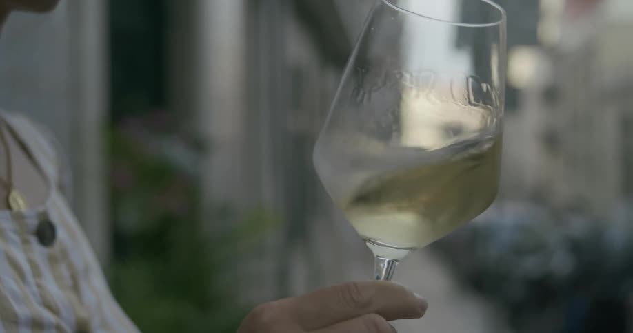 Persons hand swirling a glass of white wine