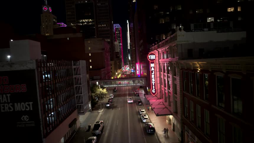Aerial view of a bustling city street with neon signs illuminating storefronts