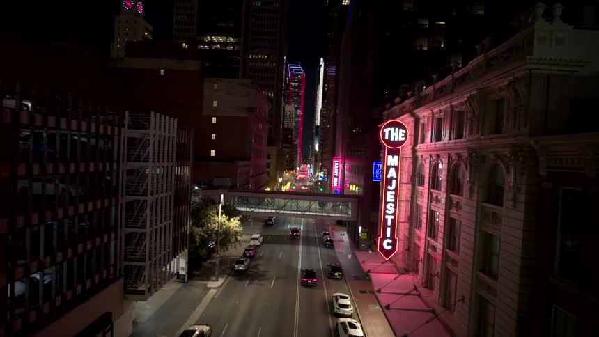 Aerial view of a street in a metropolis with large buildings illuminated at night