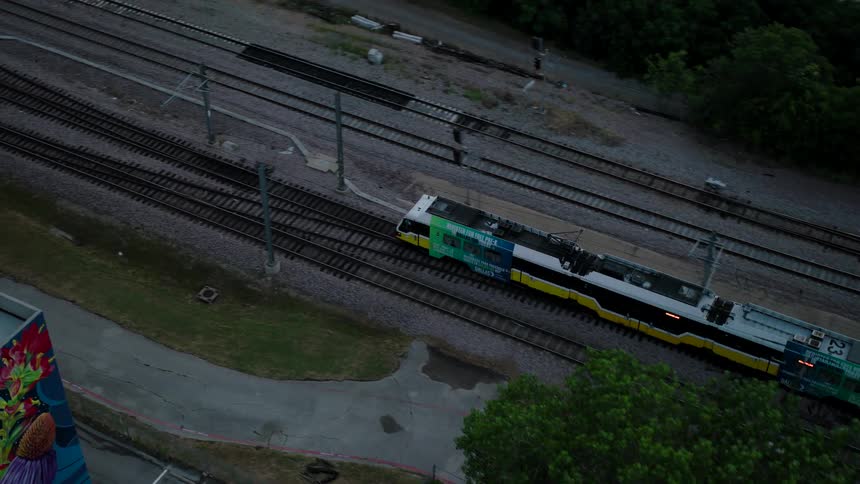 A train passes under a bridge while a truck drives on it