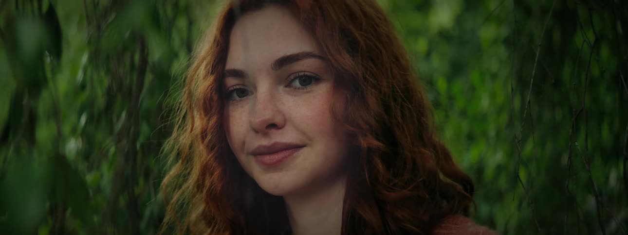 Portrait of a redhaired woman among green leaves