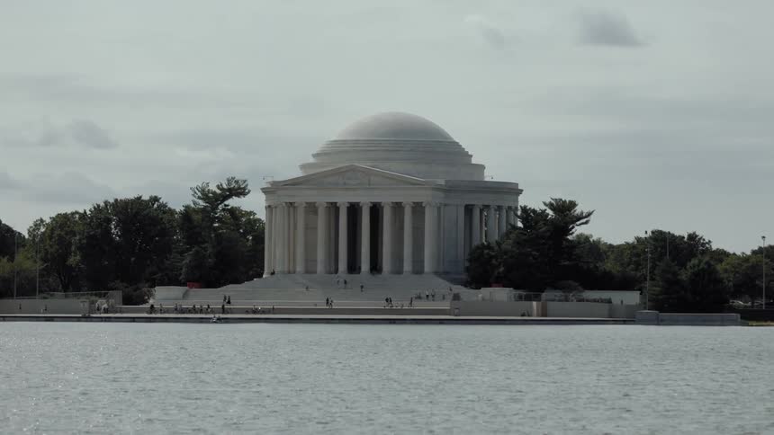 Museum with columns and classical architecture on the edge of a lake and surrounded by trees