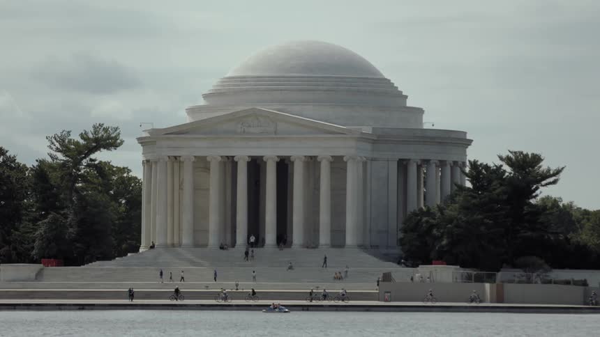 The jefferson memorial with people strolling and riding bikes in front of it