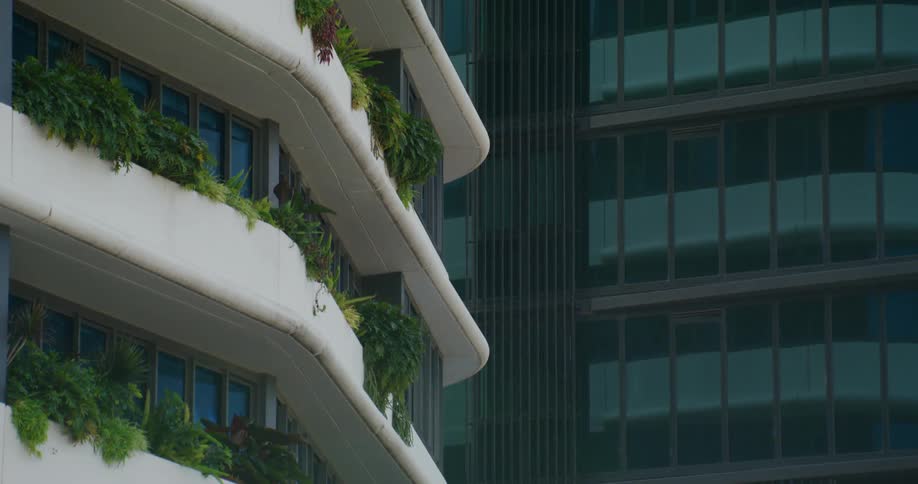 Plants trail over the sides of the external walkways on a downtown skyscraper