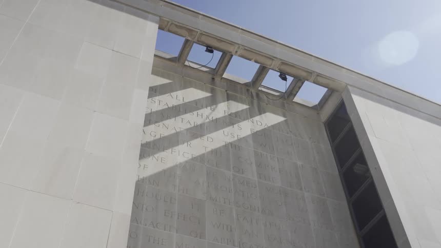 A modern concrete building with a large carved inscription on its facade