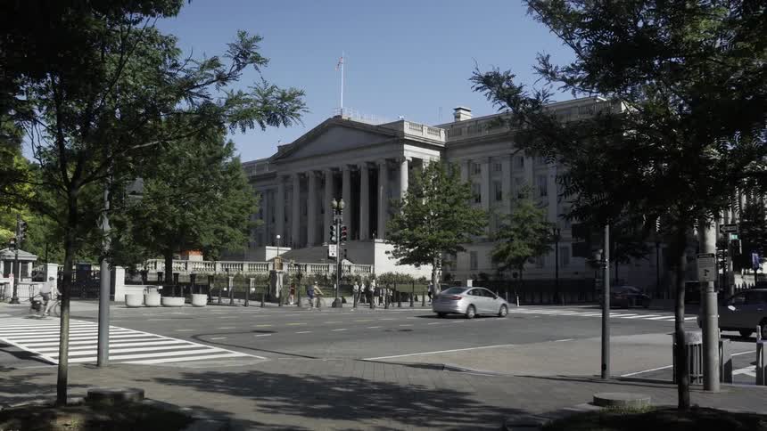 Street in a metropolis with vehicle traffic and a building with classical architecture in the background