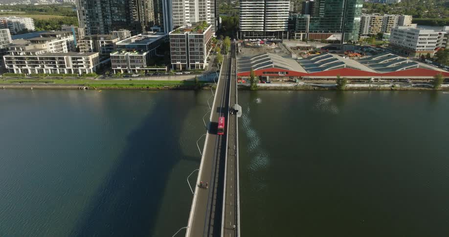 Aerial view of a long bridge above the sea with a metropolis in the background