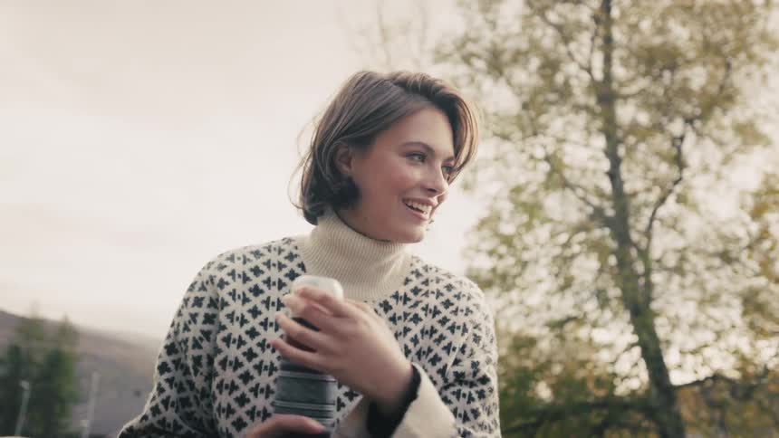 Woman closing a bottle while standing outside next to another woman