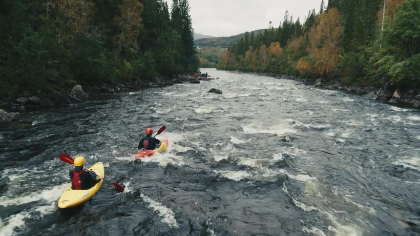 Two people kayaking down a river with a strong current