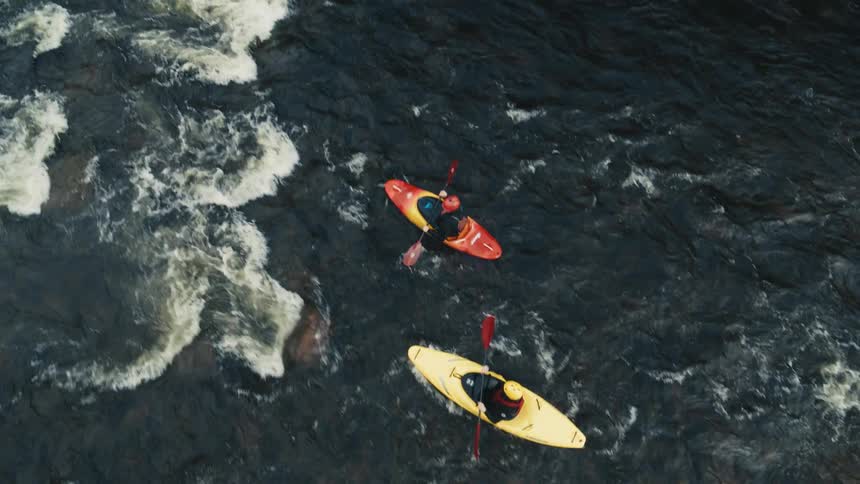 Two people kayaking on a turbulent river