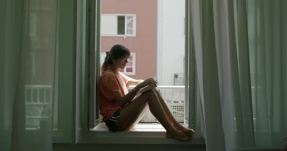 Woman sitting at the window reading a book