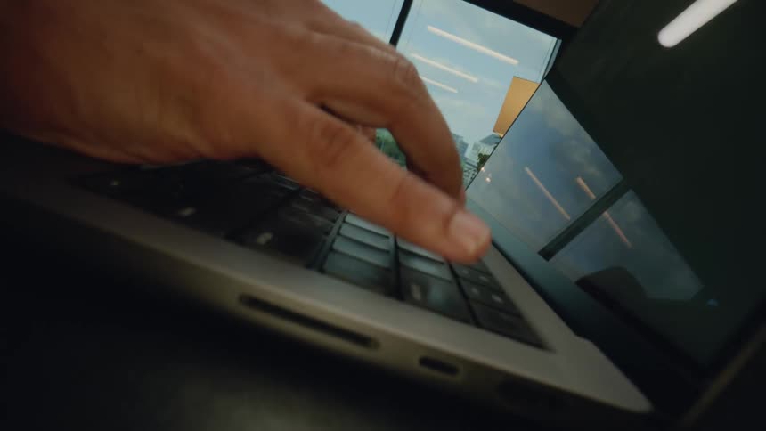 Hands typing on a laptop keyboard in an office