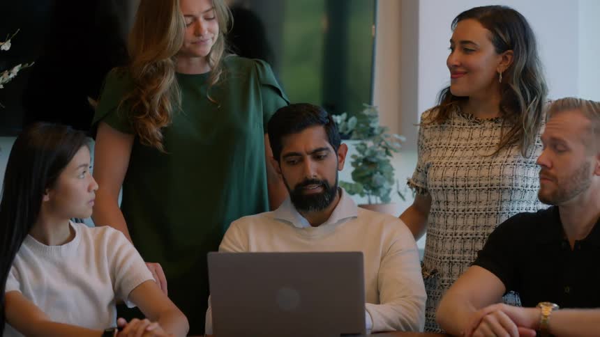 Group of people at a small table in an office talking in a meeting
