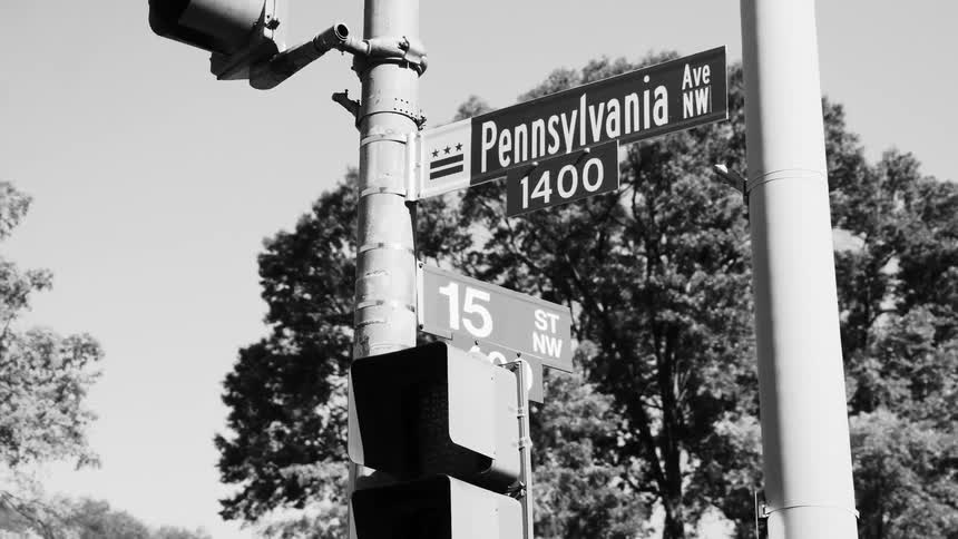 Street signs attached to a metal pole with traffic signals
