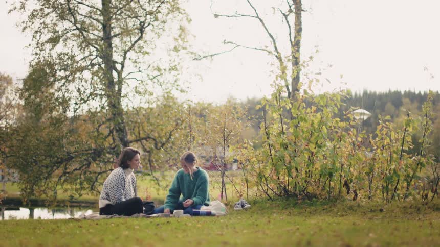 Two women sitting in a forest talking
