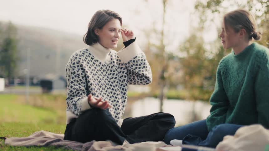 Two women sitting on the grass talking