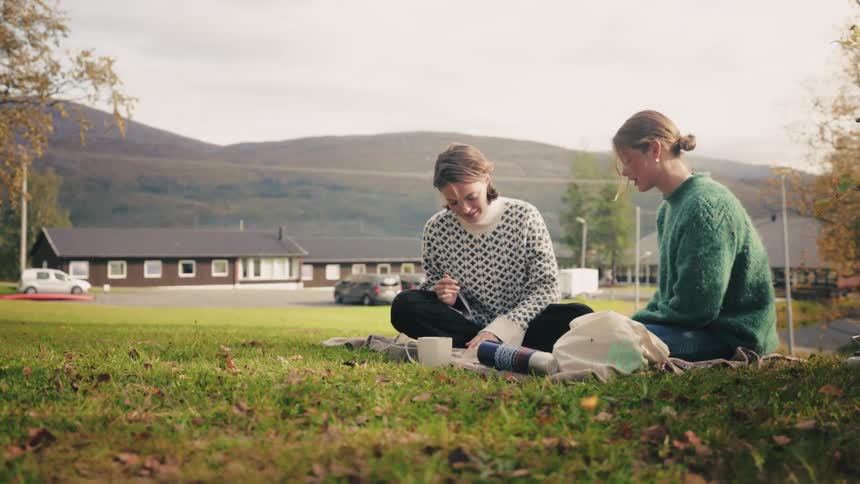 Two young women sitting on the grass talking