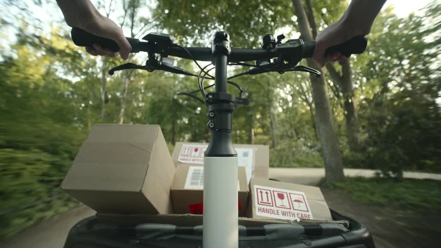 A male drives a cart with packages through a park POV