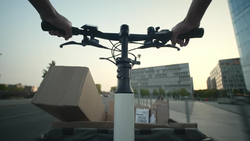 A delivery person pedaled their cargo bike through the city delivering packages to customers POV
