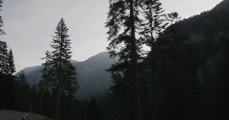 Vehicle drives down a winding road with high mountains in the background