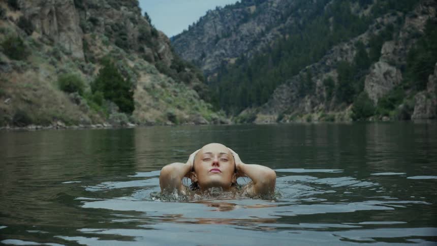 Woman coming out of the water of a lake with her hands on her head