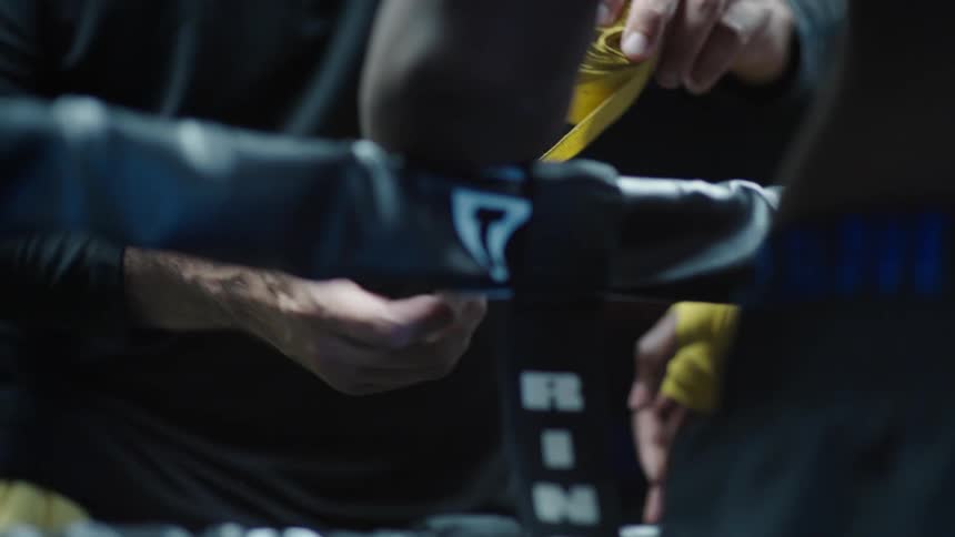 A coach tapes up a boxers hand
