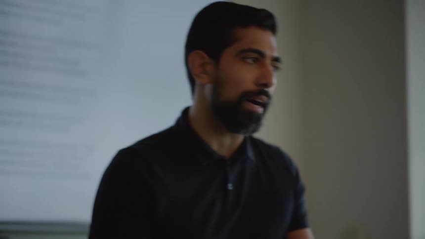 Bearded man communicating with a screen in the background