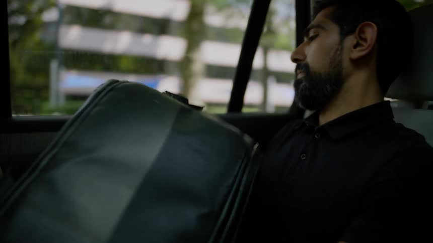 Man inside a moving car rummaging through his backpacks