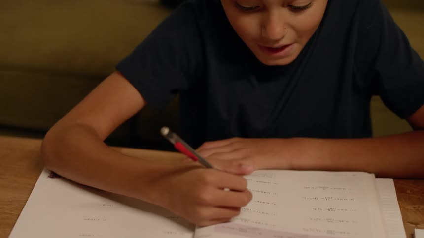 Mother next to her young son who is doing a school assignment