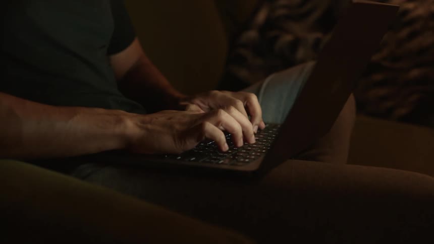 Person sitting on sofa typing on laptop