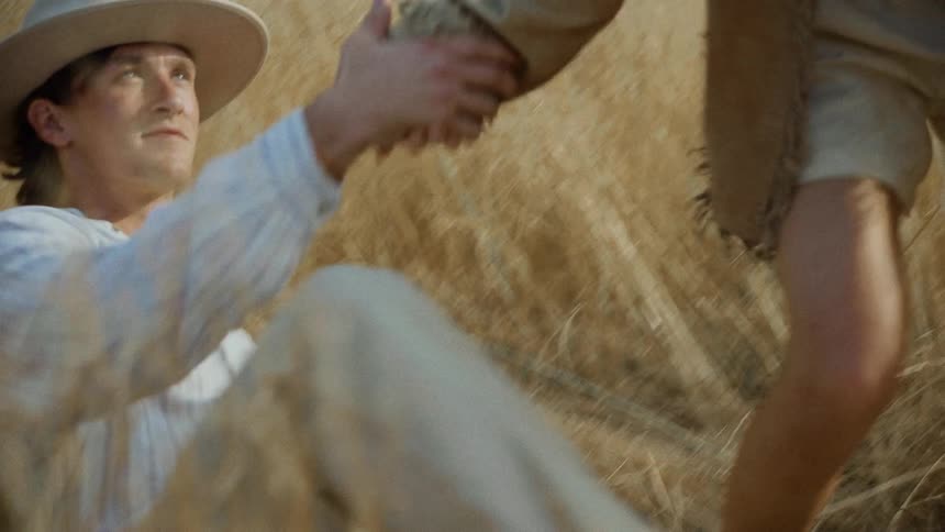 Woman rising from reeds and pulling her boyfriend by the hands in a field