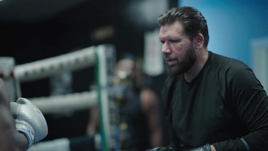 Two boxers spar for practice in a ring at a gym