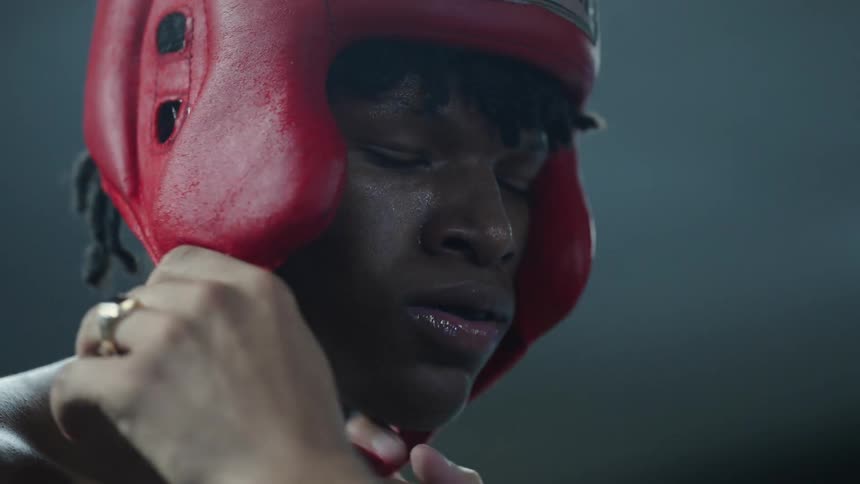 Man helps a boxer remove his protective headgear