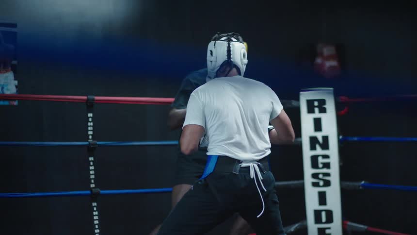 Two men sparring in a boxing ring wearing gloves and headgear