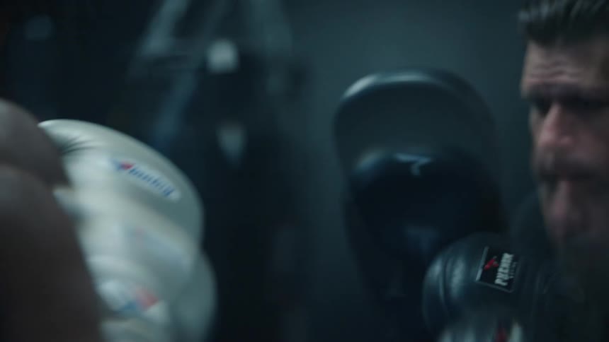 Two boxers spar for practice in a ring in a gym