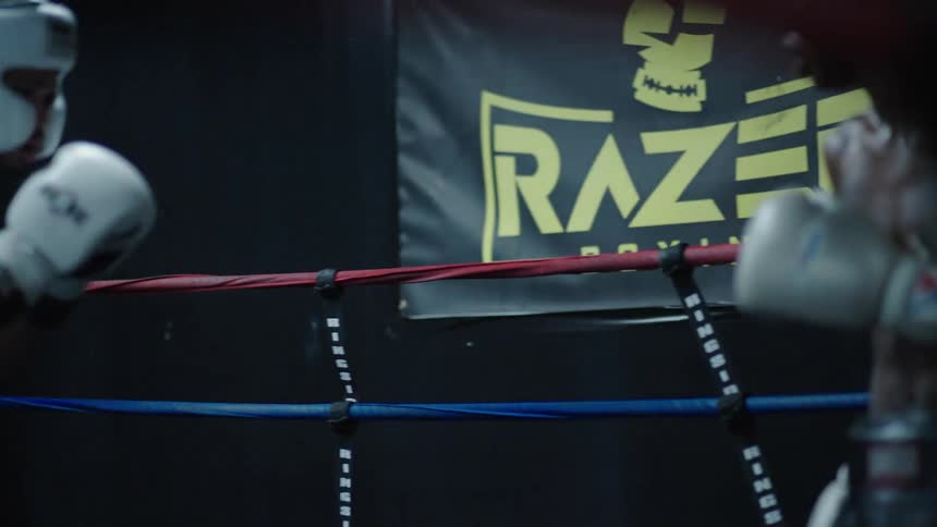 Trainer watches boxers spar in the boxing ring