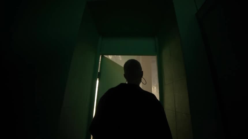 View of a woman from behind opening the door and entering a hall