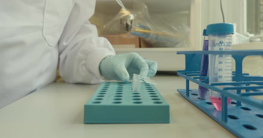 Gloved hand manipulating a pipette and pouring clear liquid